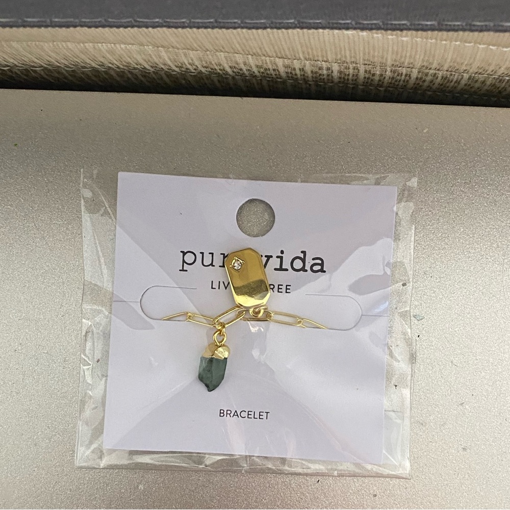 Pura vida gold linked chain bracelet with green crystal and gold charm.